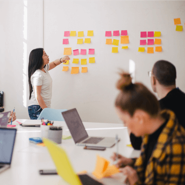 Stagiaire travaillant sur un tableau blanc avec des post-it pendant une formation professionnelle